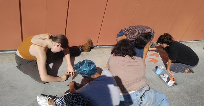 Student volunteers painting dinosaur footprints linking our current museum with our previous museum