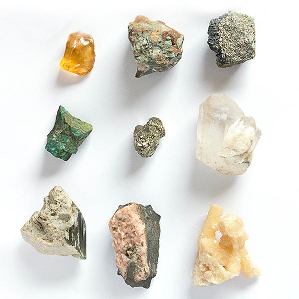 Nine different minerals arranged on a white background