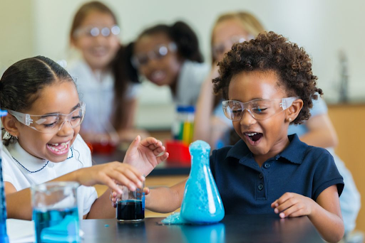 two kids doing an experiment with blue foam while other kids watch in the background