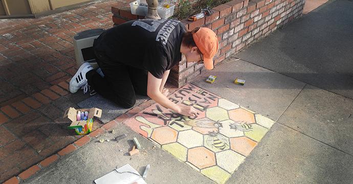 Intern Logan Naylor drawing bees as part of Pastels on the Plaza.