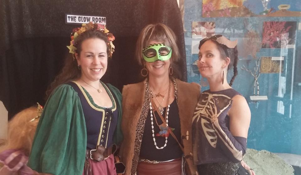 Volunteers in costume pose in front of glowing rock booth 