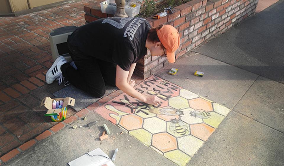 Intern Logan Naylor drawing bees as part of Pastels on the Plaza