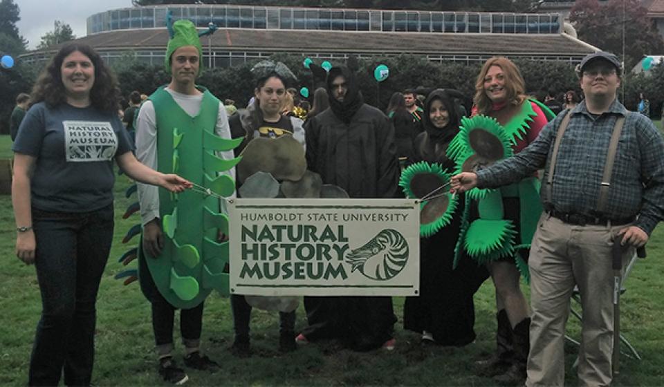 Group of NHM employees and students in a field posing for the camera